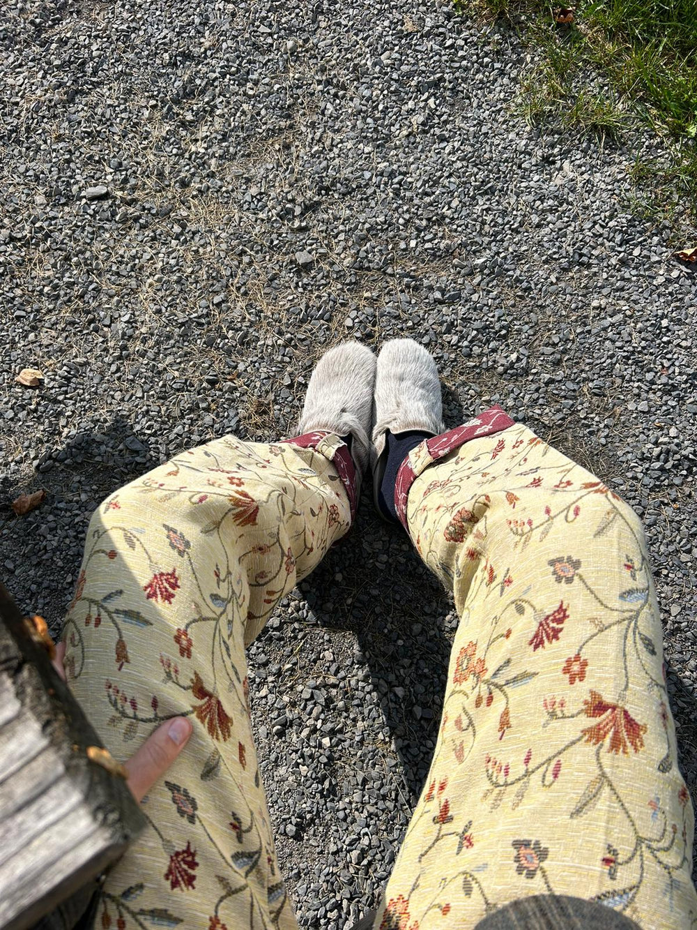 Person wearing floral pants and gray shoes on a gravel path