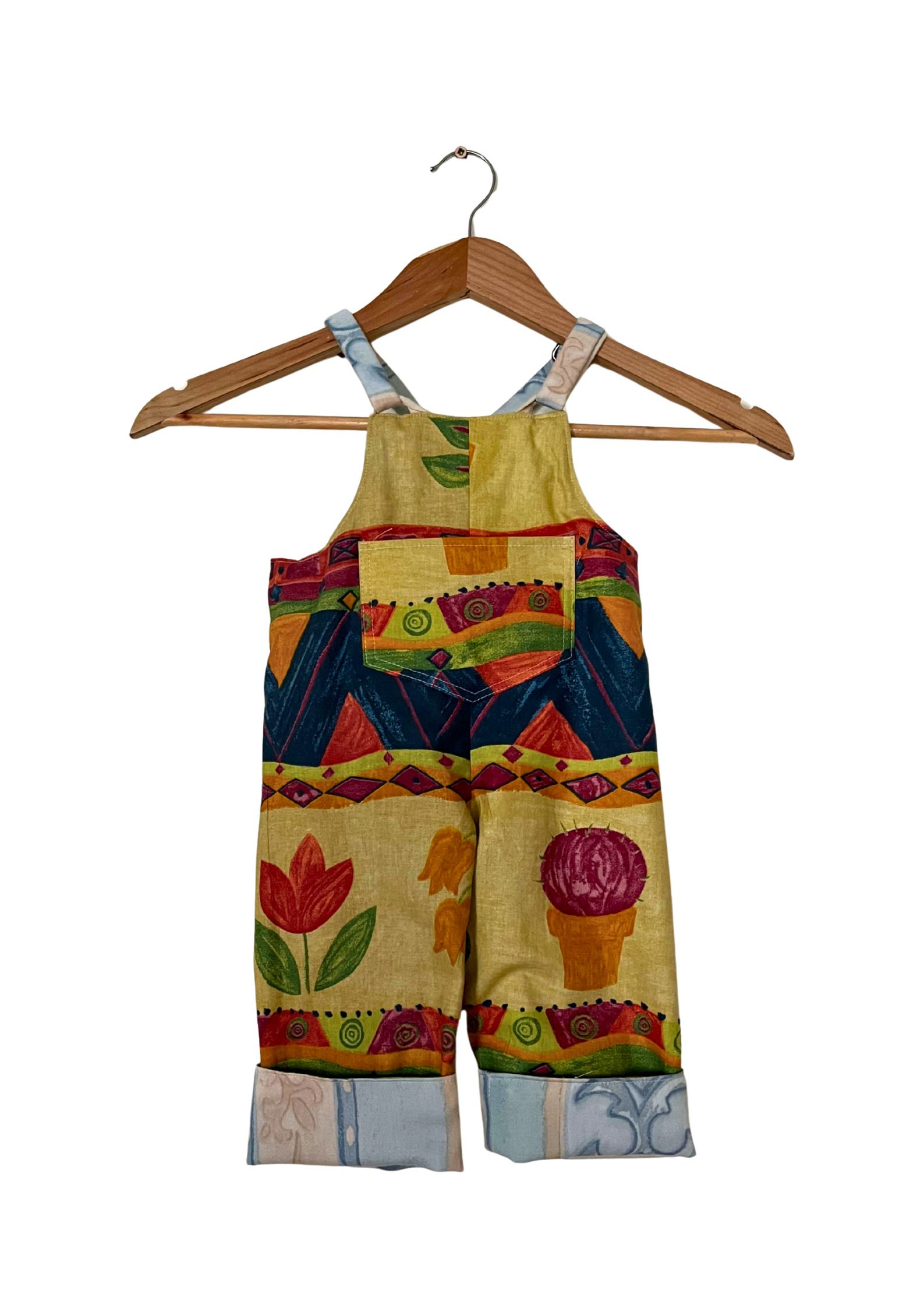 Colorful children's overalls on a wooden hanger against a white background