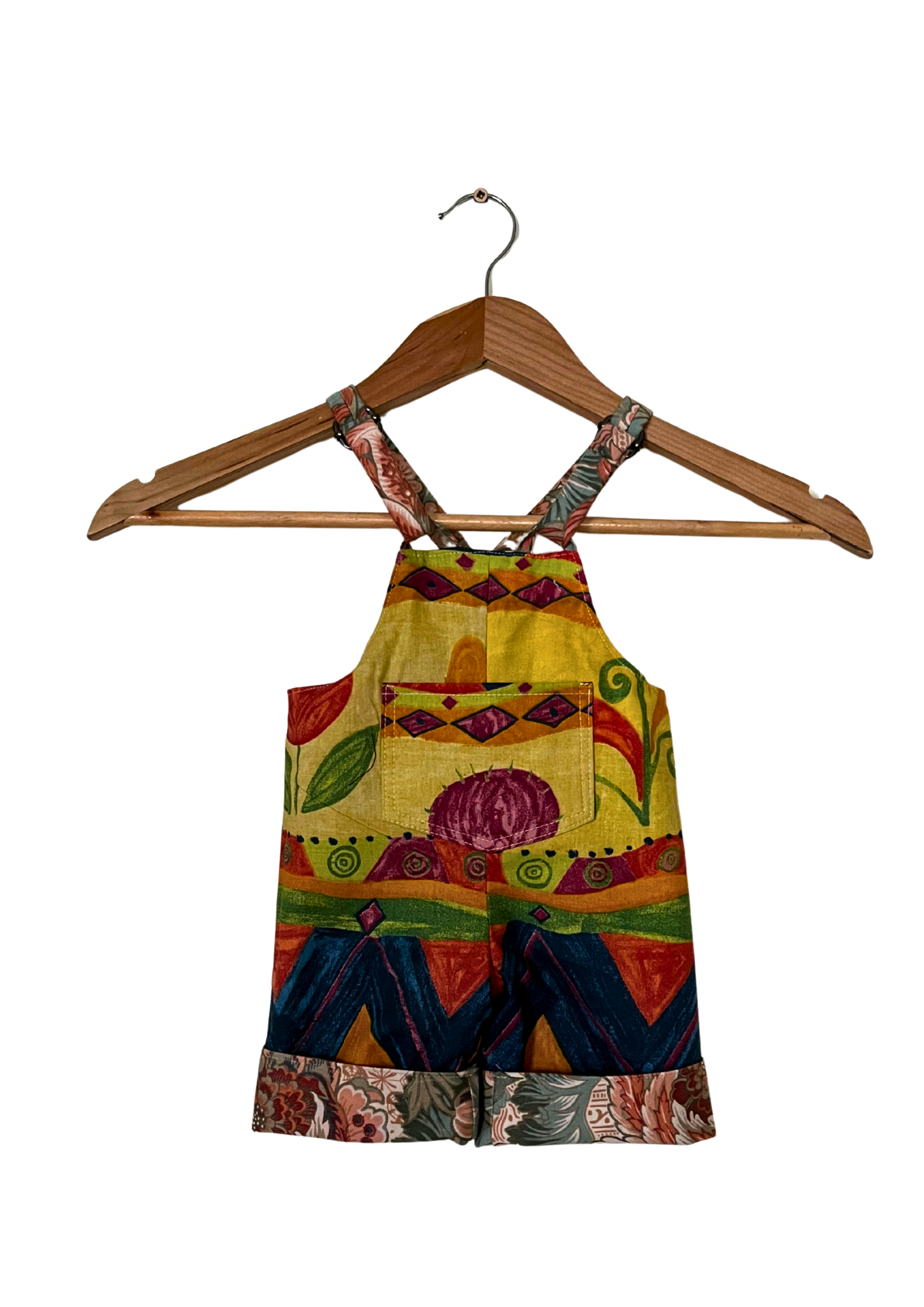 Colorful children's dress with floral patterns on a wooden hanger against a white background