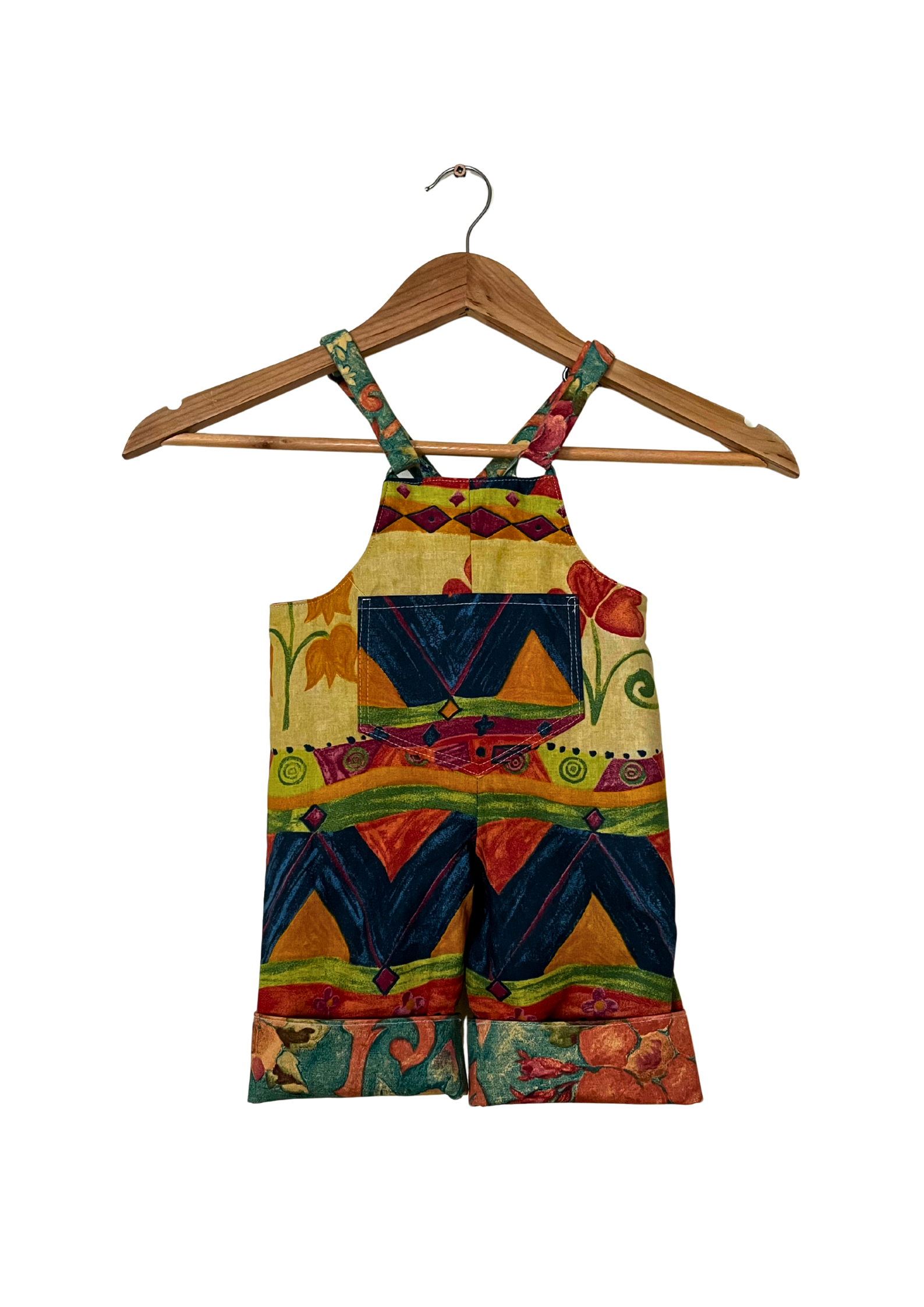 Colorful children's overalls on a wooden hanger against a white background