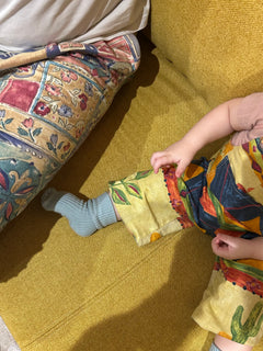 Child playing with a colorful bag on a patterned couch