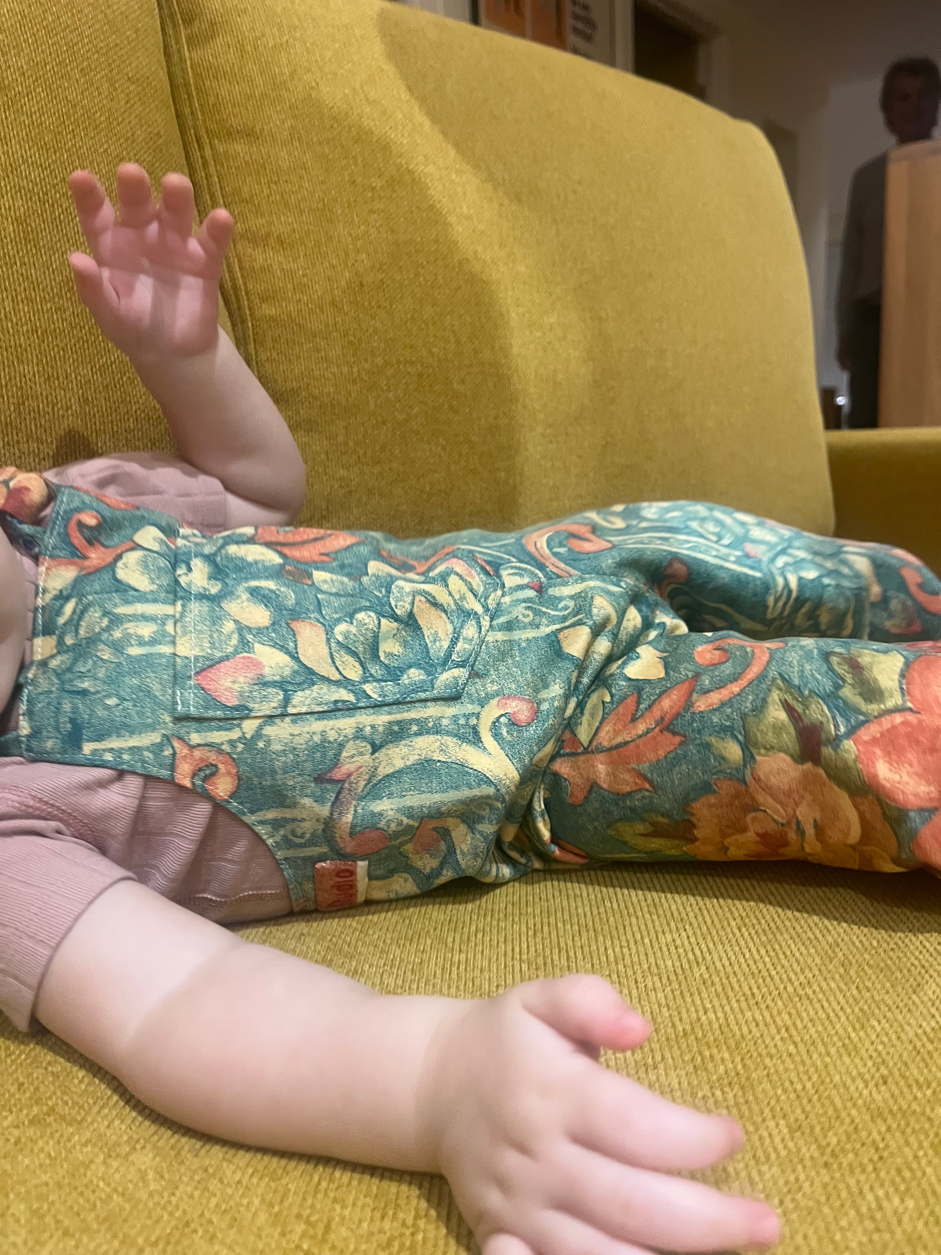 Child wearing floral leggings sitting on a yellow couch
