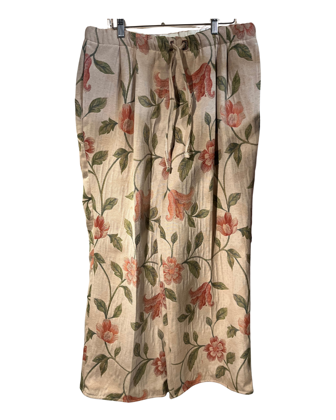 Floral patterned pants on a hanger against a white background