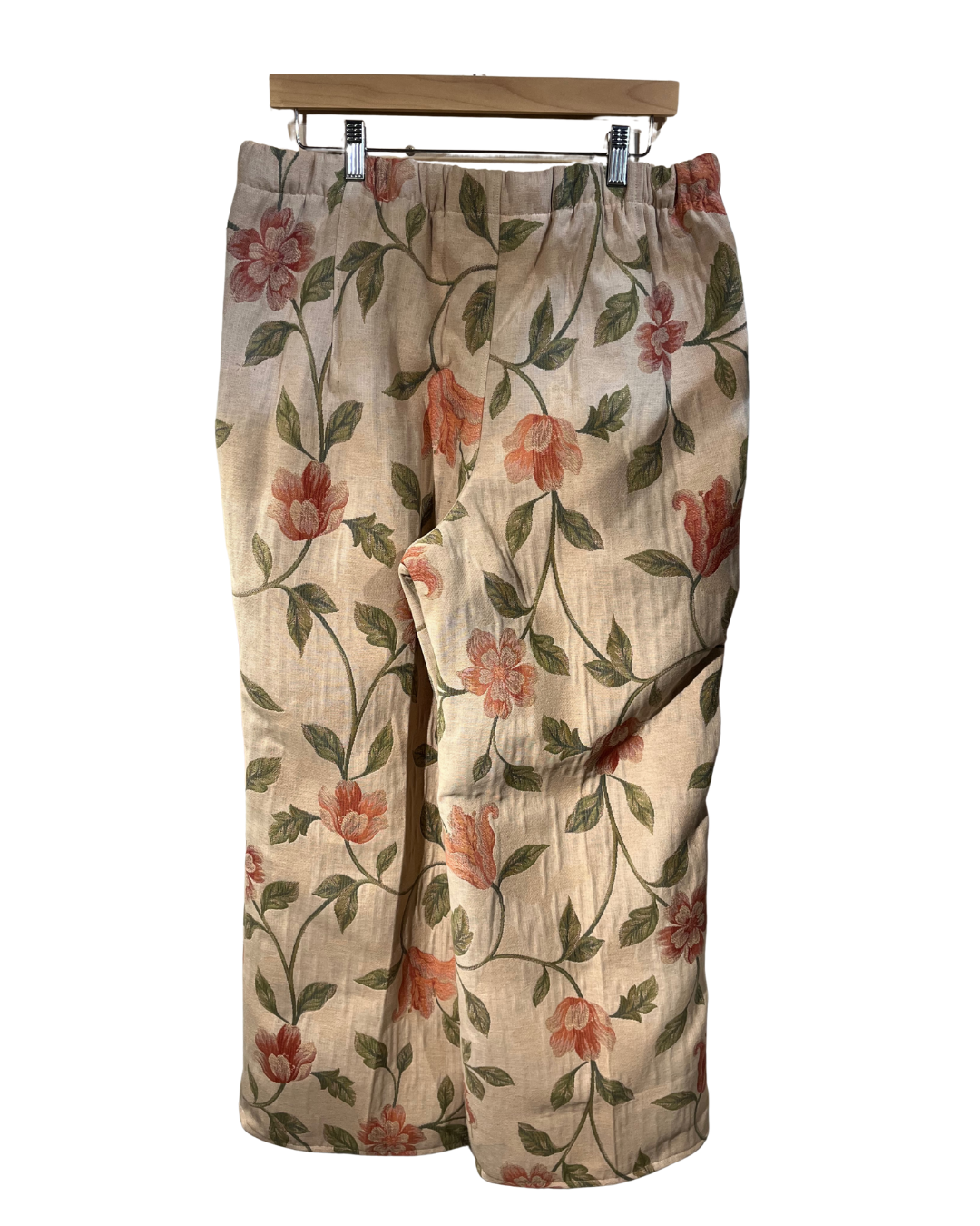 Floral-patterned pants on a hanger against a white background