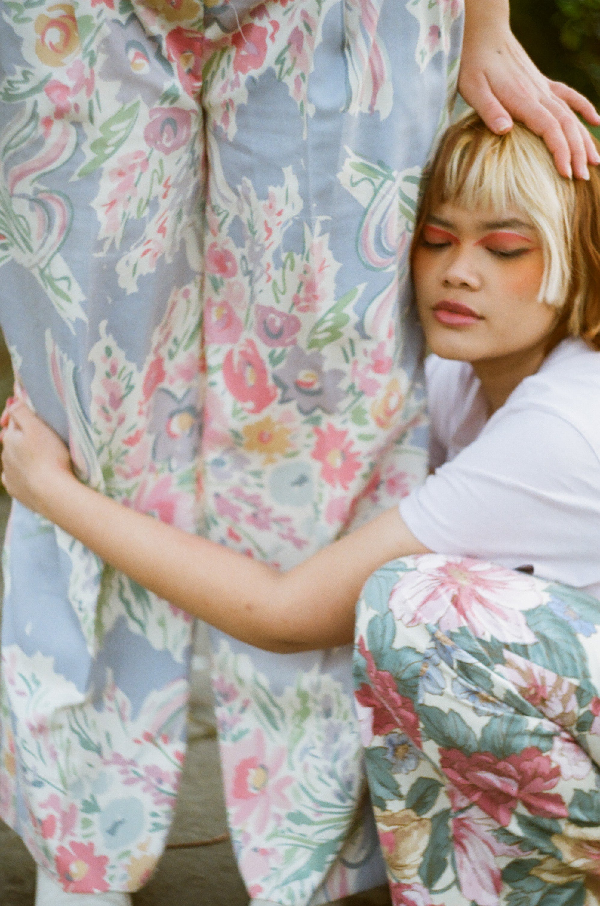 Two people wearing floral outfits with a blurred background