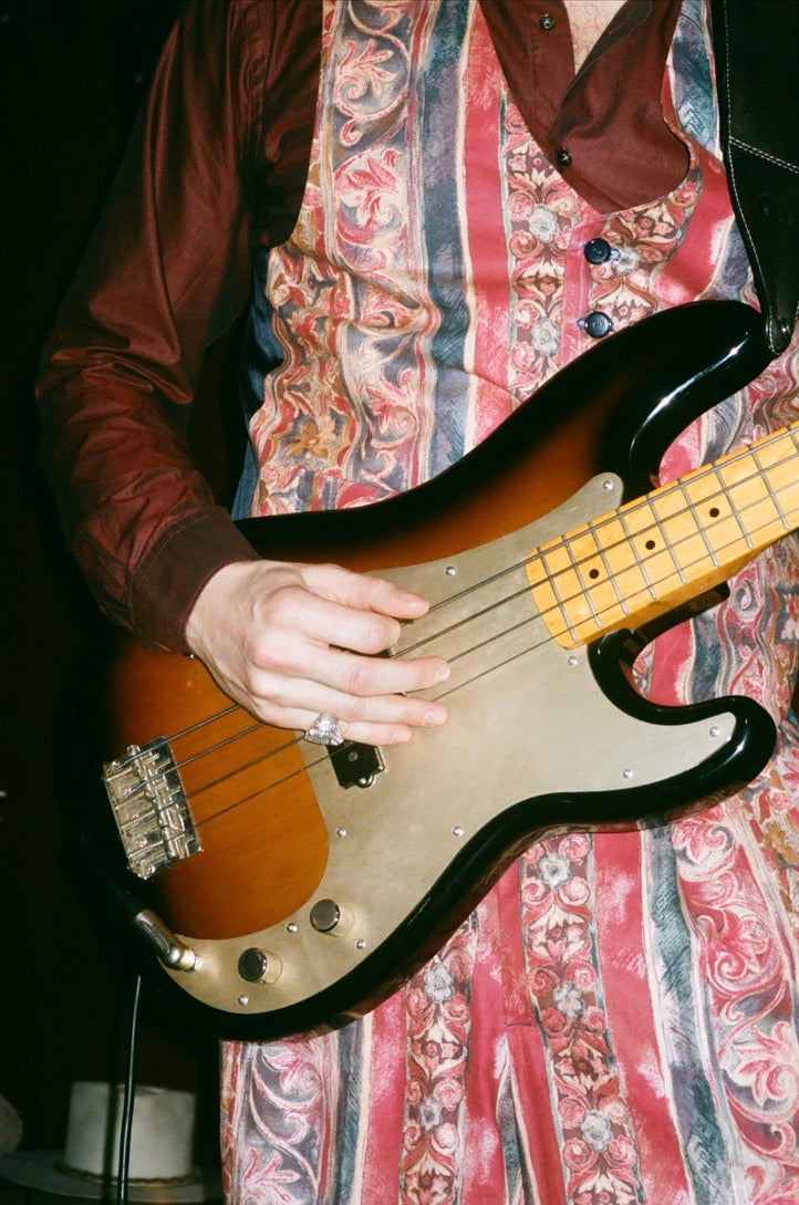Person playing a bass guitar with a patterned suit