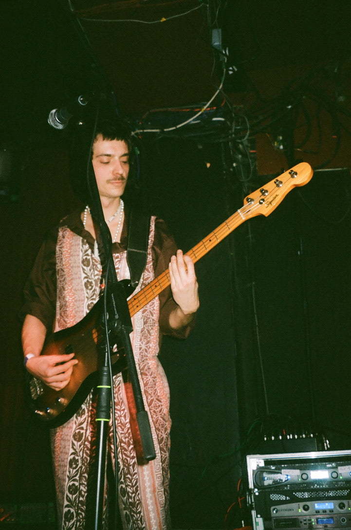 Person playing a bass guitar on stage with a dark background