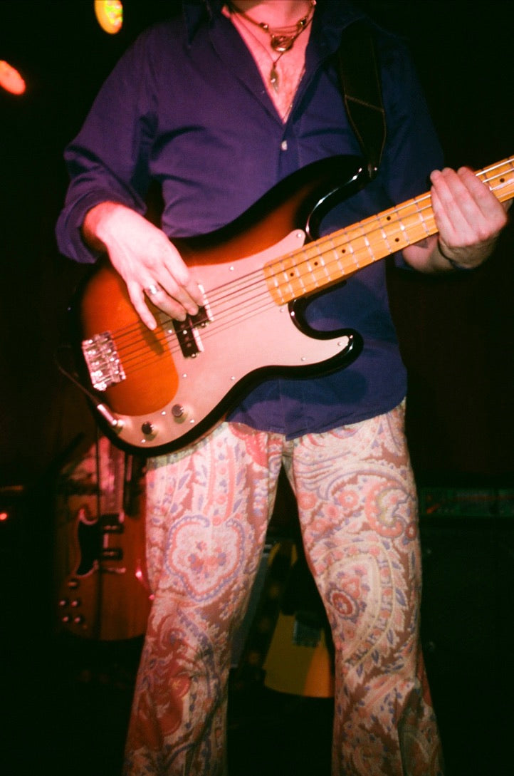 Person playing a bass guitar on stage with a dark background