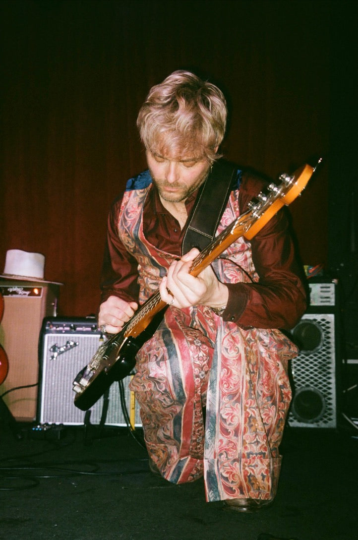 Person playing guitar on stage with amplifiers in the background