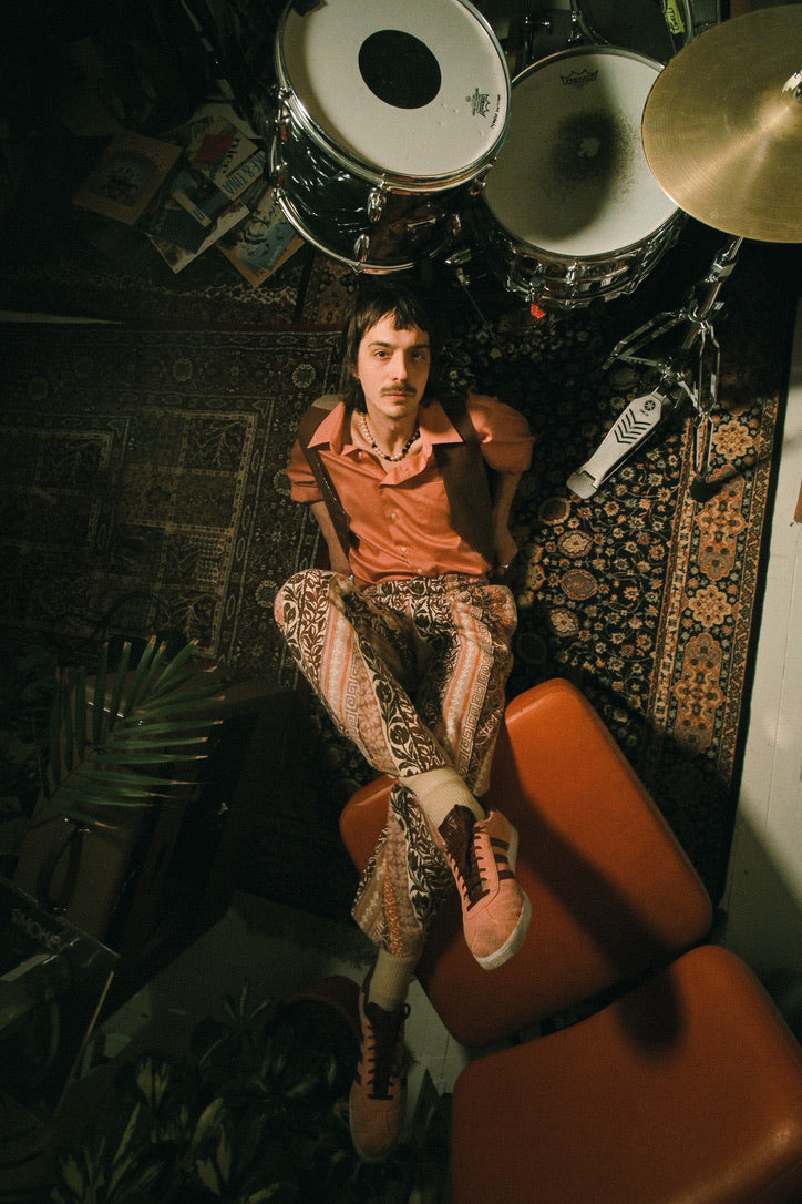 Person sitting on a chair with a drum set in the background