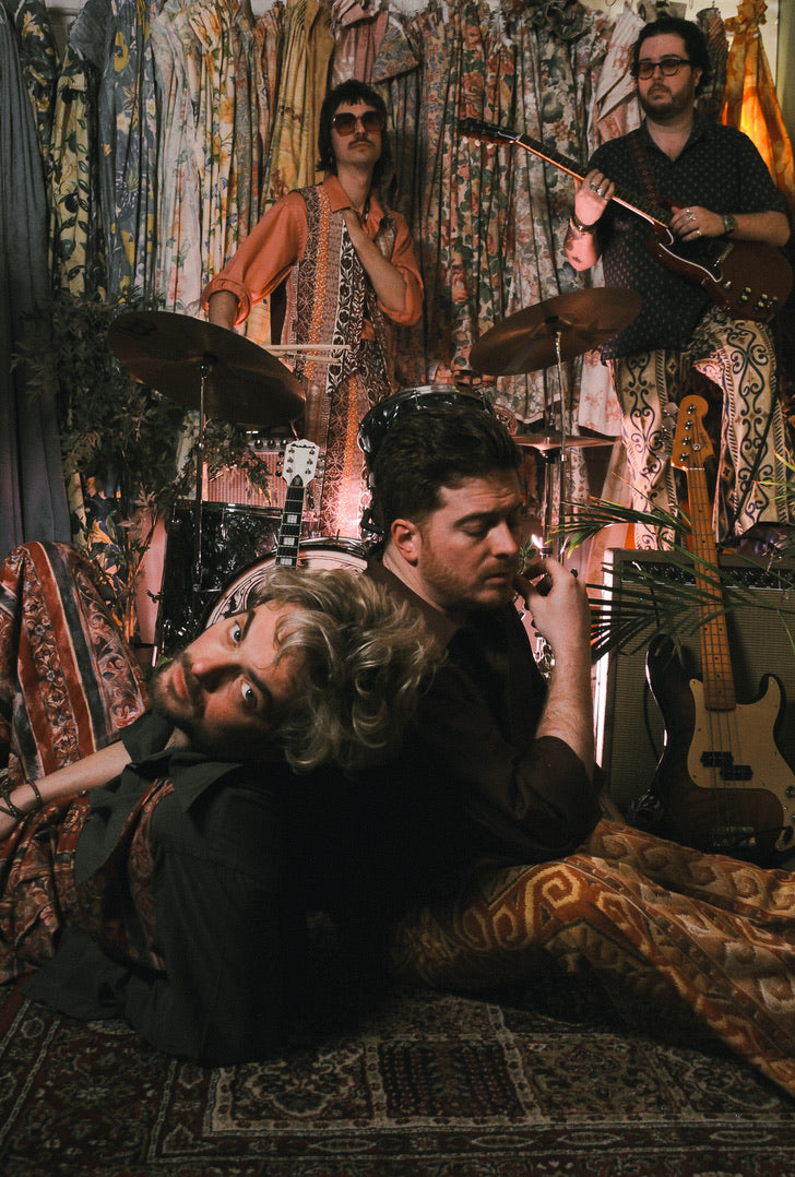 Band performing in a decorated room with patterned walls and furniture.