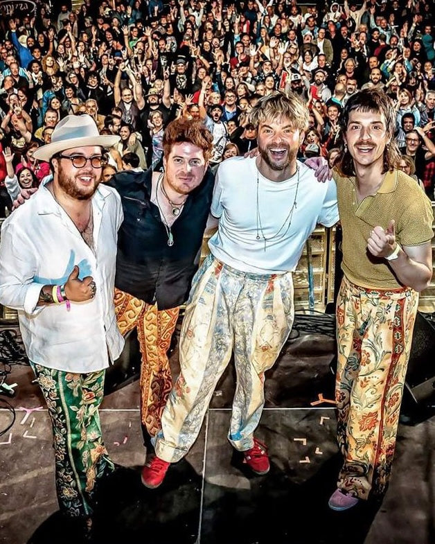 Four men posing together with a crowd in the background