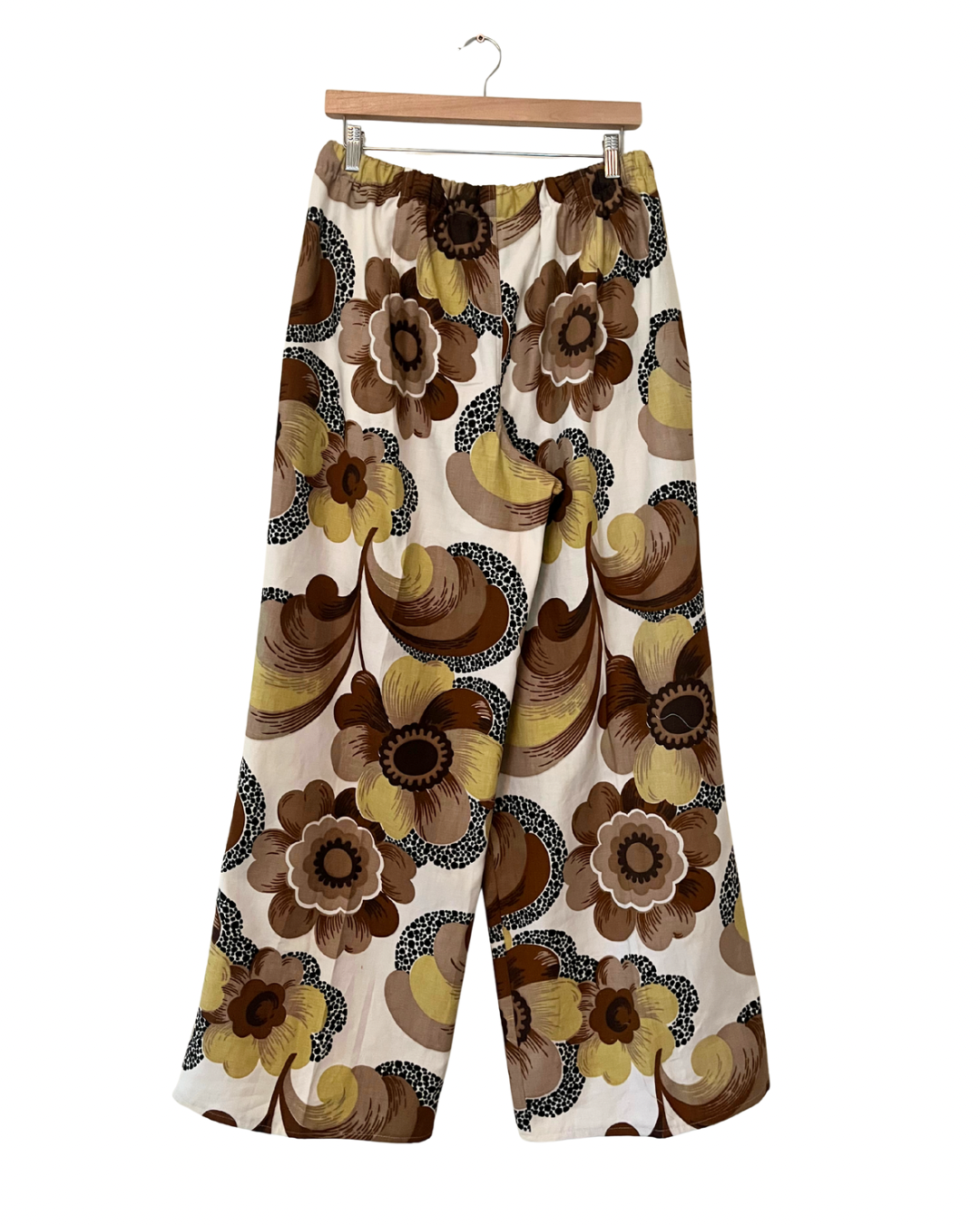 Floral patterned pants on a hanger against a white background