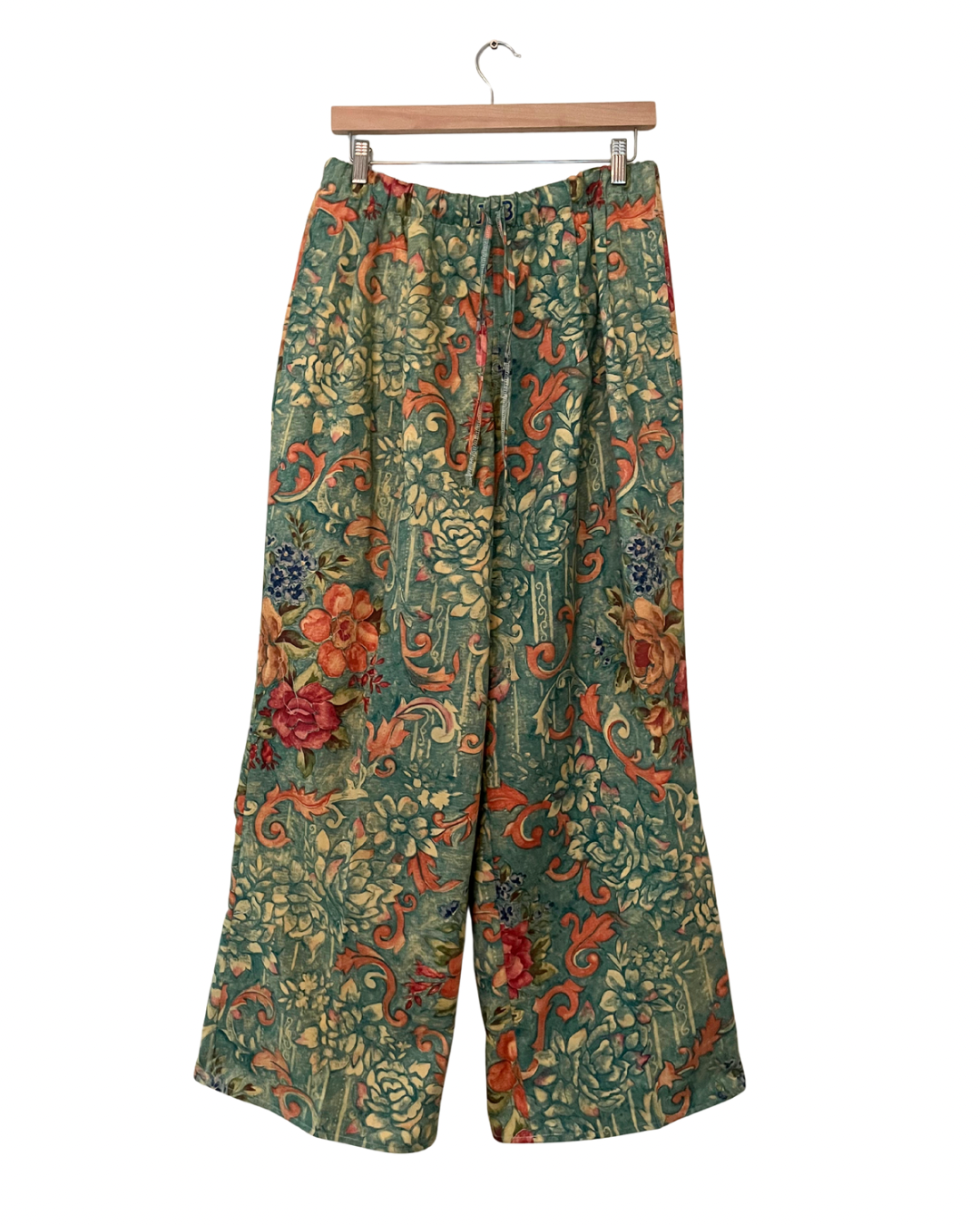 Floral-patterned pants on a hanger against a white background