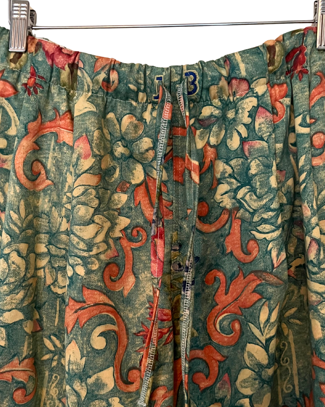 Floral patterned fabric with red and green colors on a metal rod.
