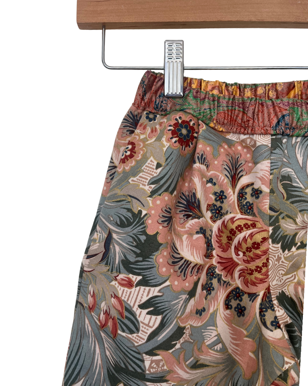 Floral patterned childrens trouser on a hanger against a white background