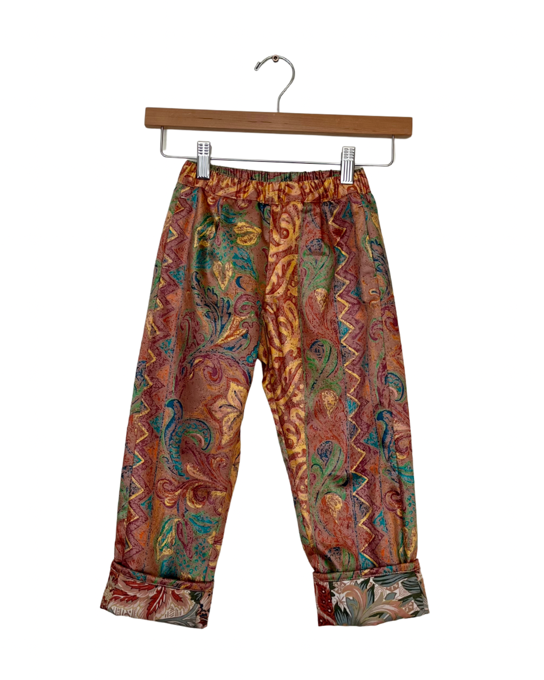 Colorful patterned pants on a hanger against a white background