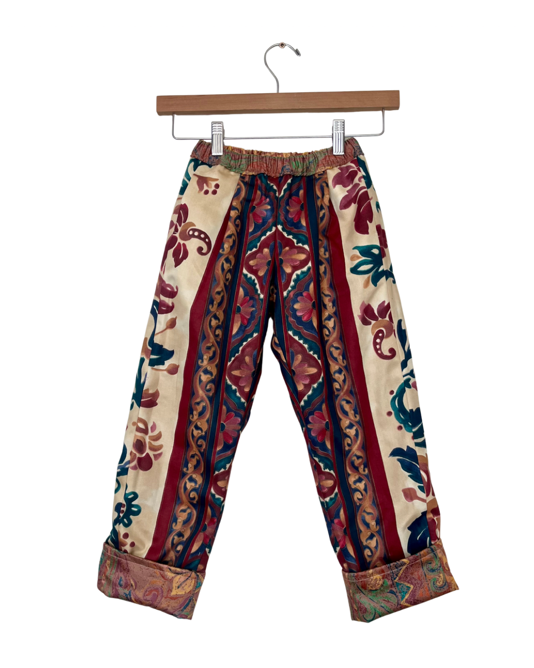 Colorful patterned pants on a hanger against a white background