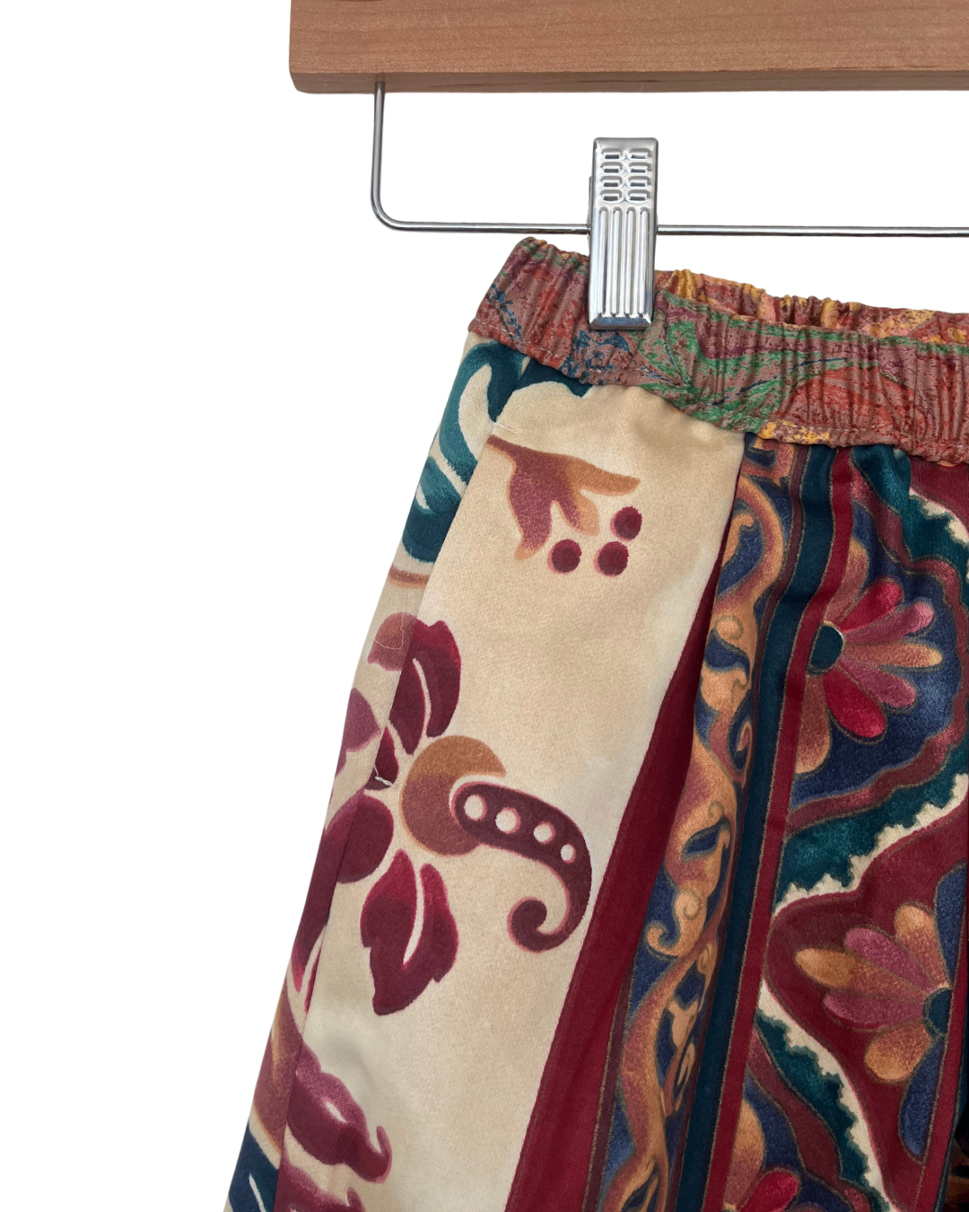 Colorful patterned pants on a hanger against a white background