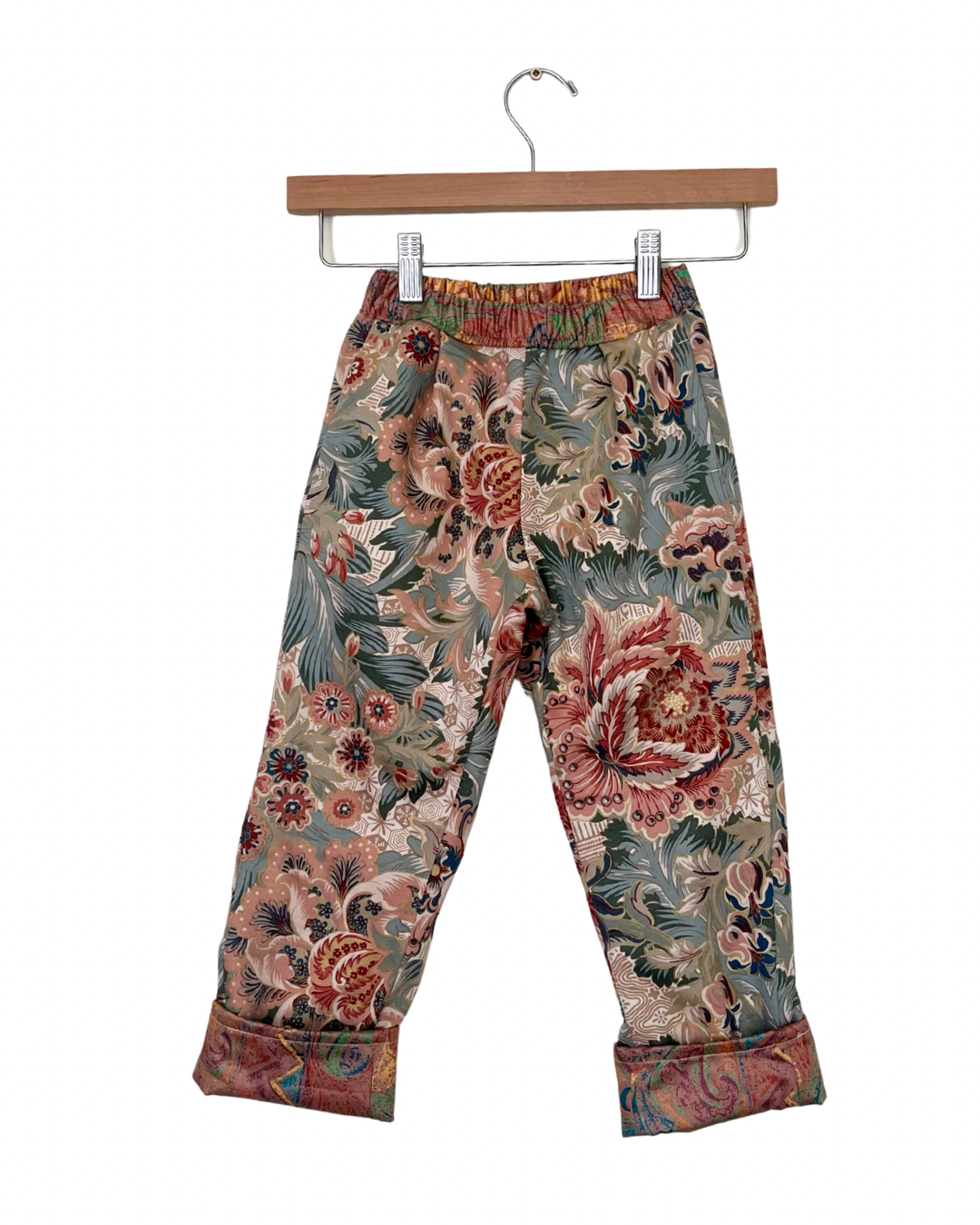 Floral patterned pants on a hanger against a white background