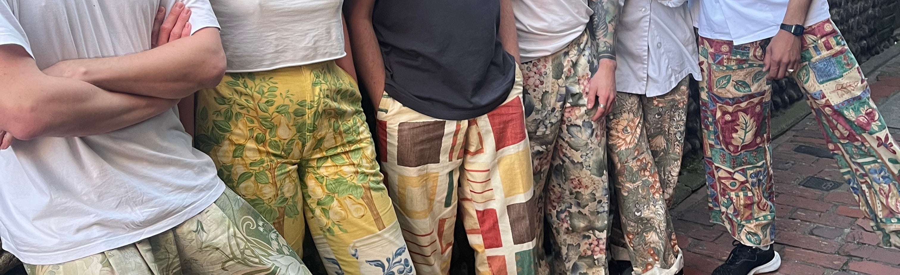 People wearing patterned pants standing together on a street.