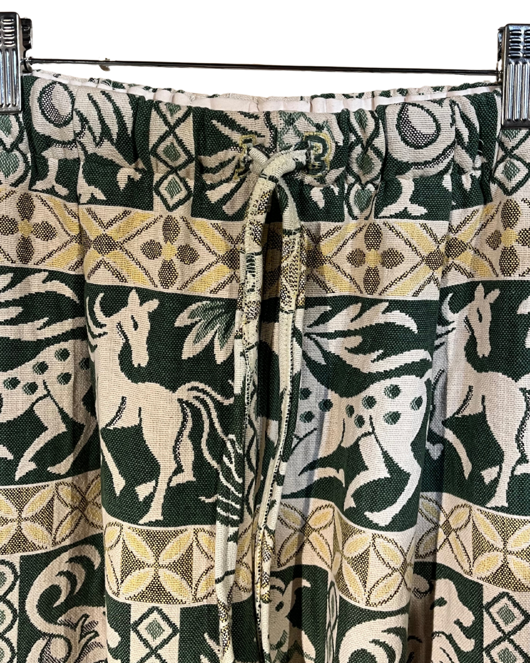 Curtains with a pattern of animals and geometric shapes in green, beige, and white.
