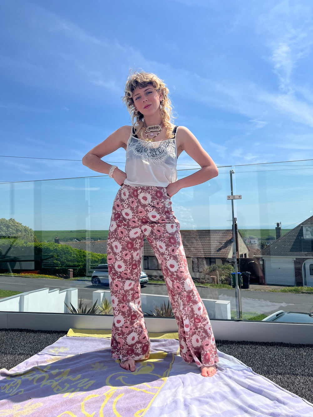 Person wearing a floral outfit standing outdoors with a clear blue sky.