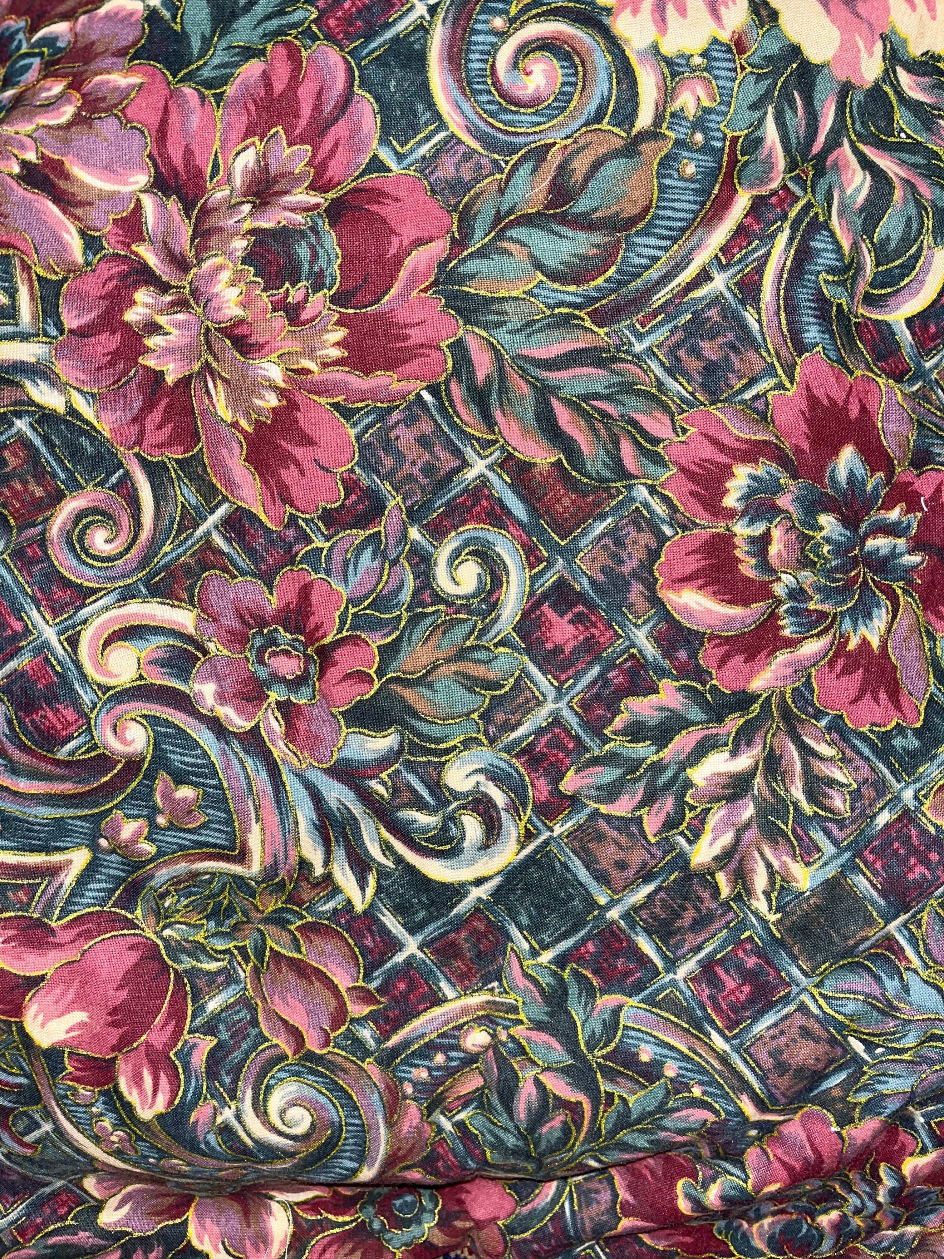 Decorative fabric with floral and geometric pattern in pink, green, and black.