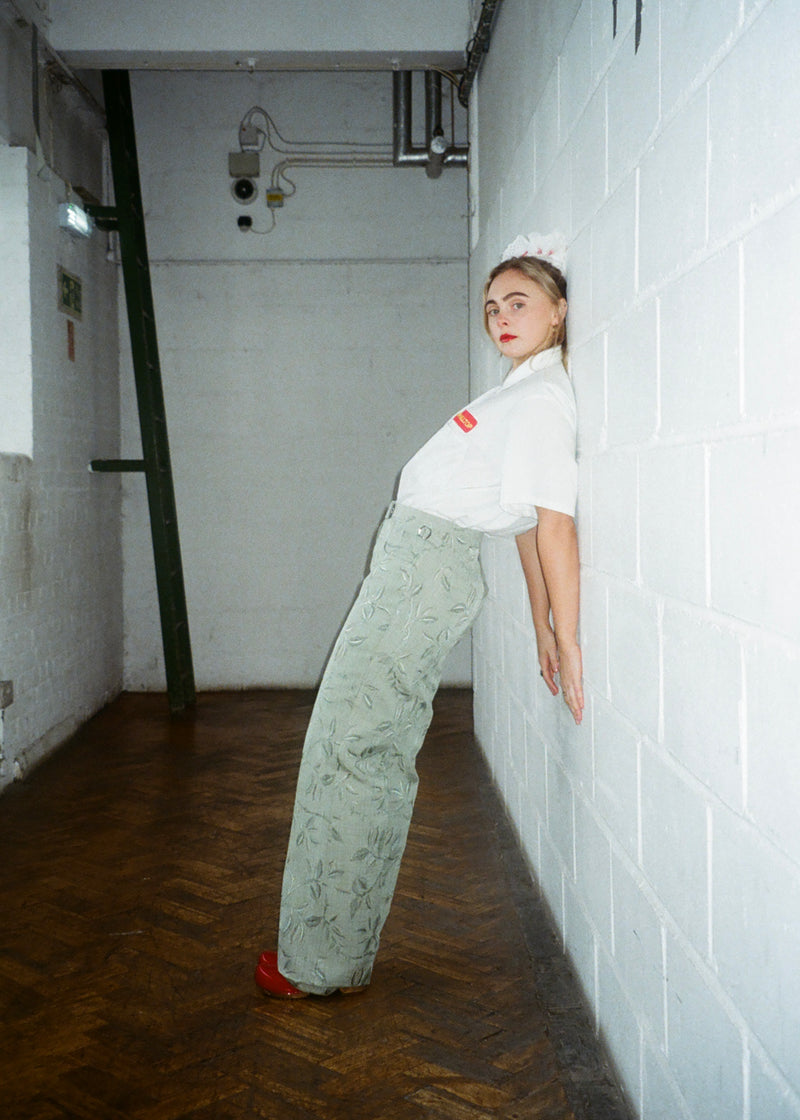 Person leaning against a white tiled wall in an industrial setting