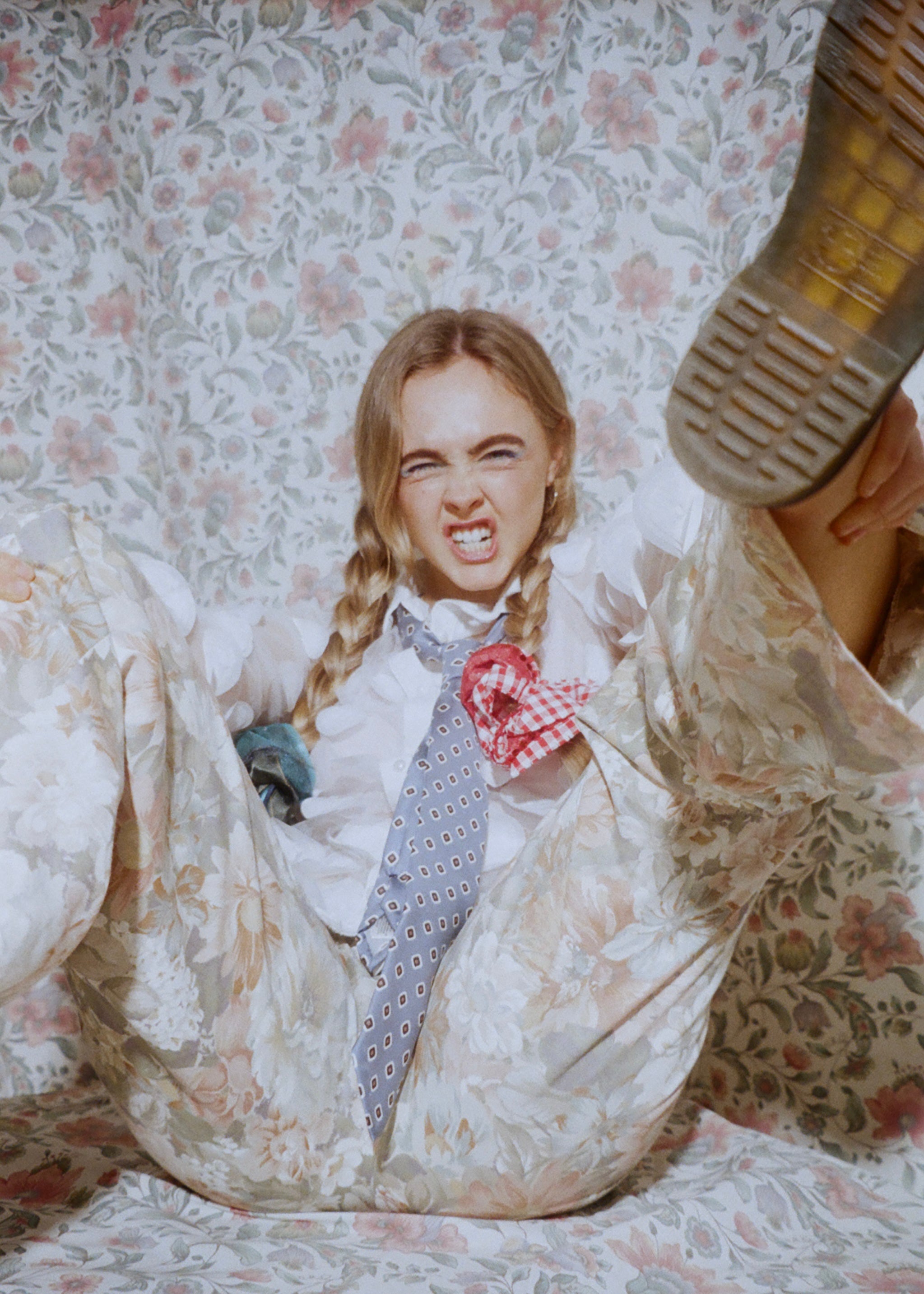Person in a white dress with a checkered bow, sitting on a floral-patterned couch.