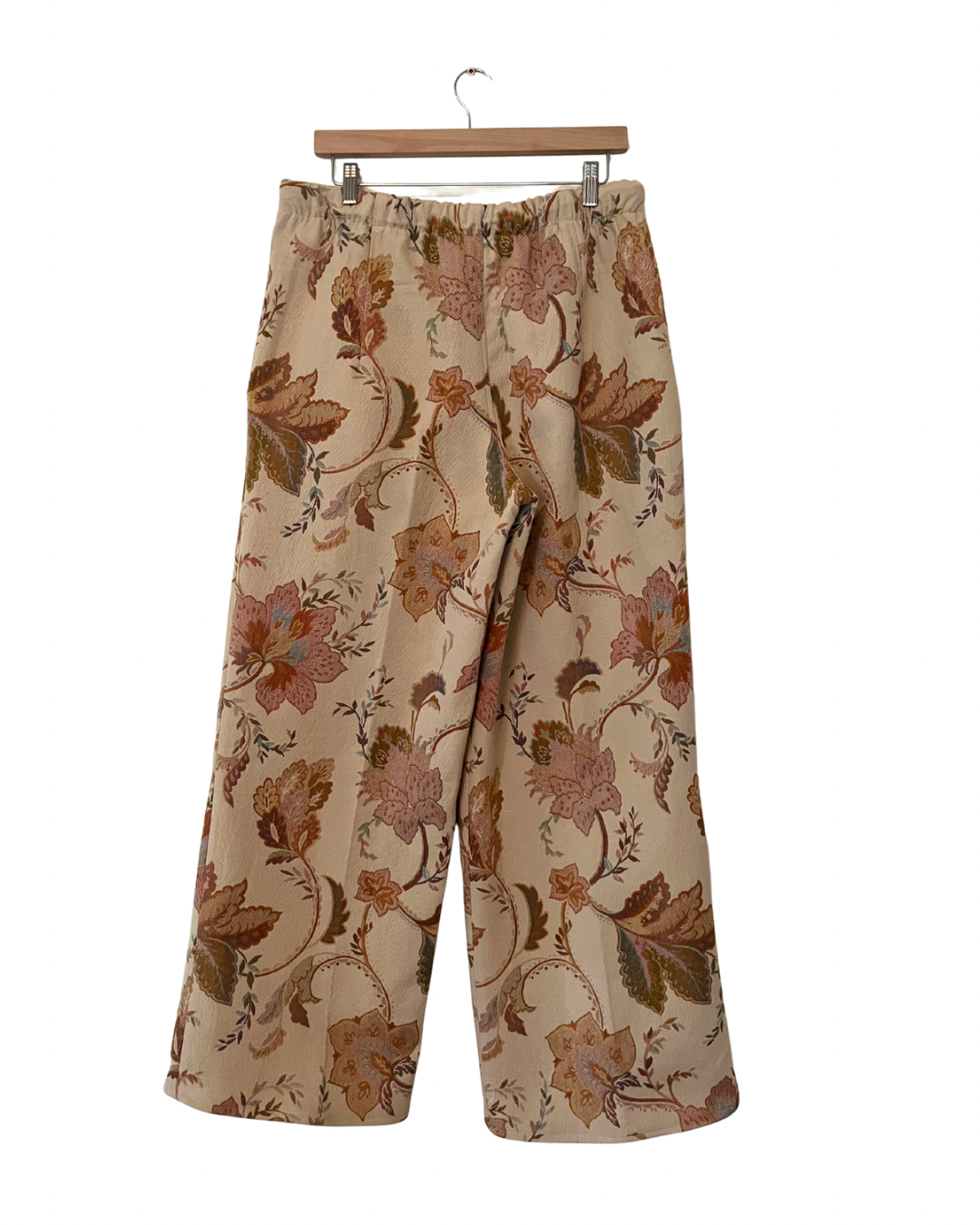 Floral-patterned pants on a hanger against a white background