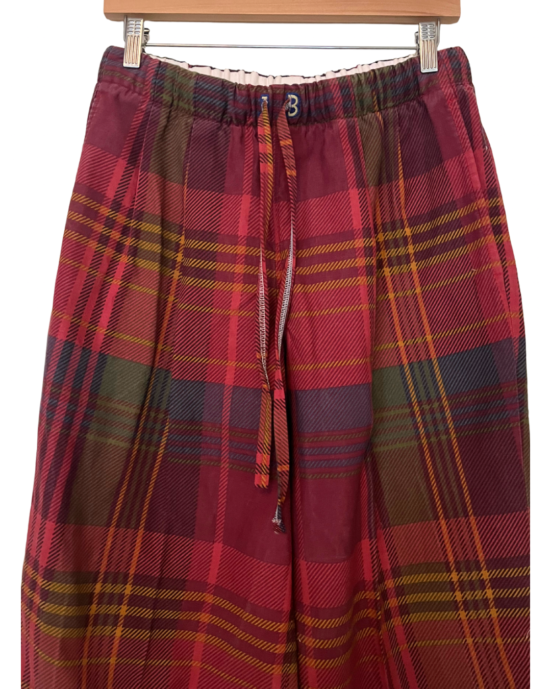 Red plaid skirt on a hanger against a white background