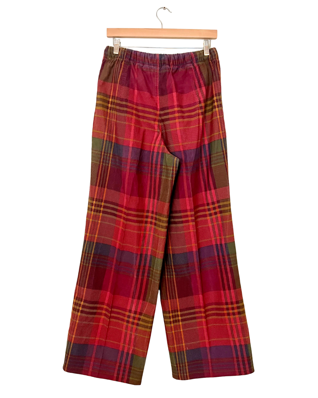 Red plaid pants on a hanger against a white background