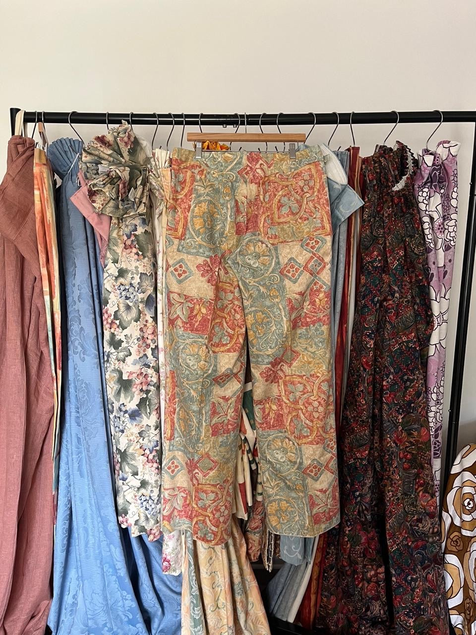 Collection of patterned dresses on a rack against a plain wall.