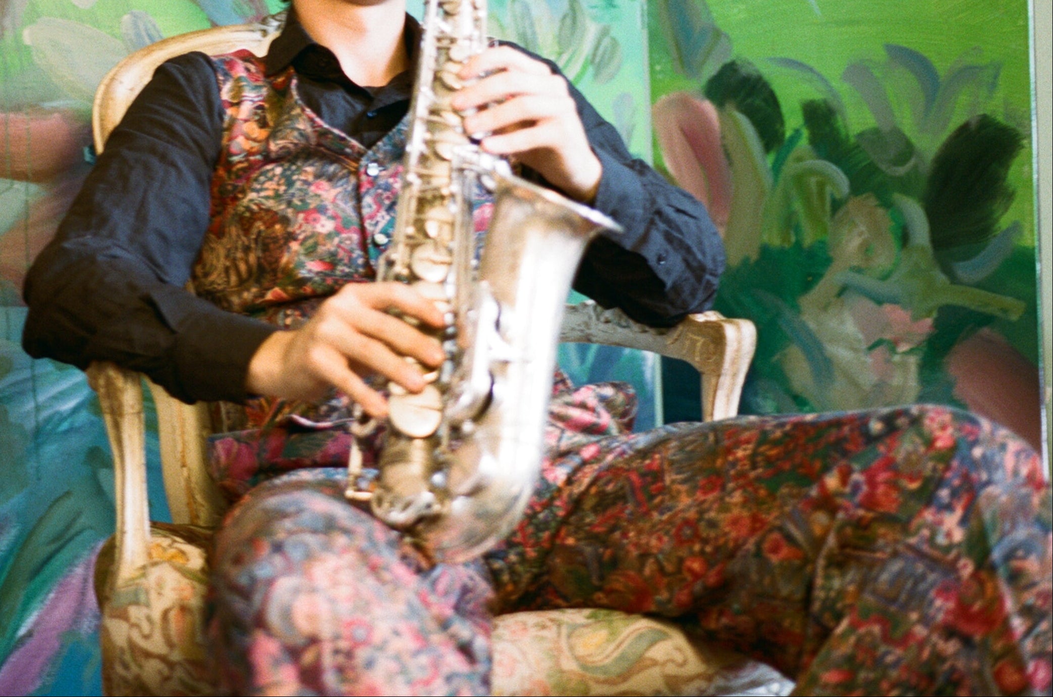 Person playing a saxophone with a colorful, abstract background