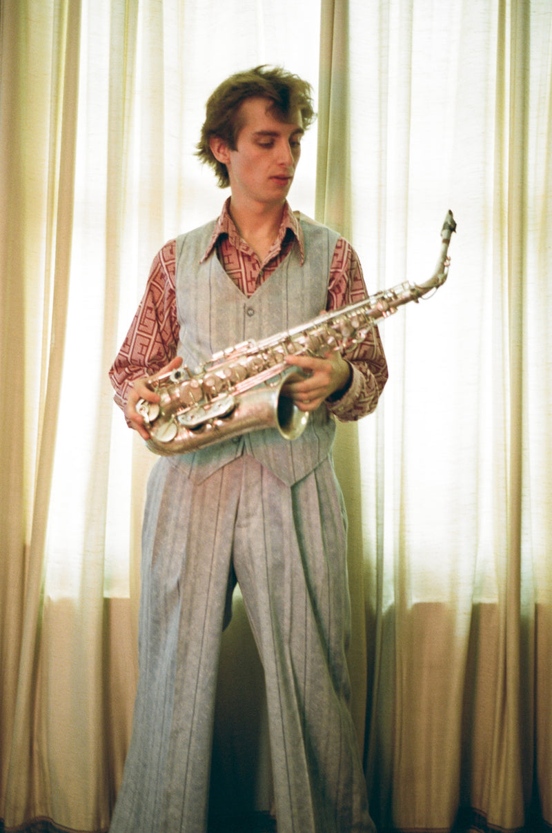 Man holding a saxophone in front of light curtains