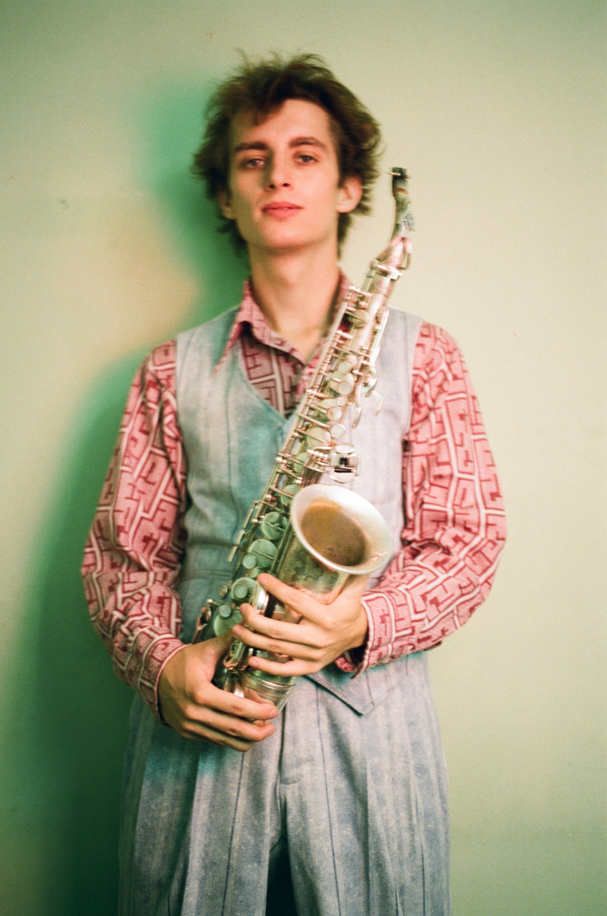 Person holding a saxophone against a plain background