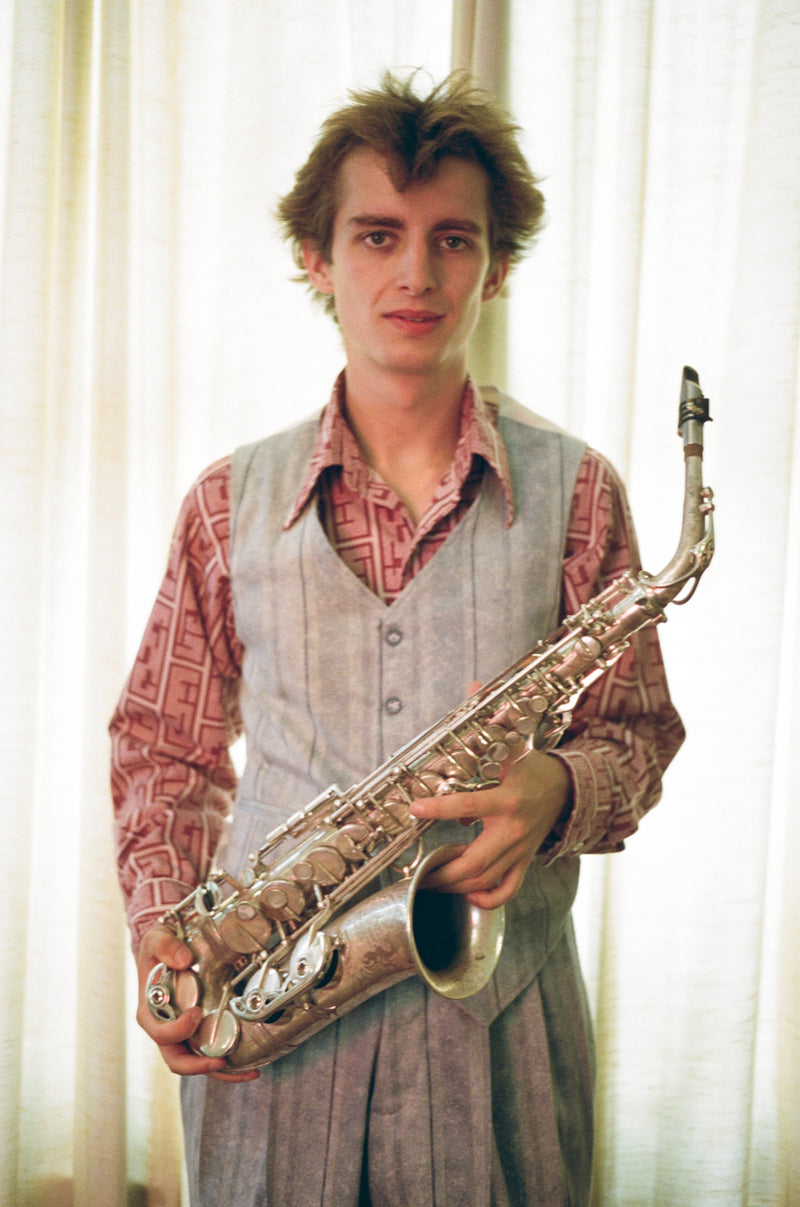 Man holding a saxophone in front of light curtains