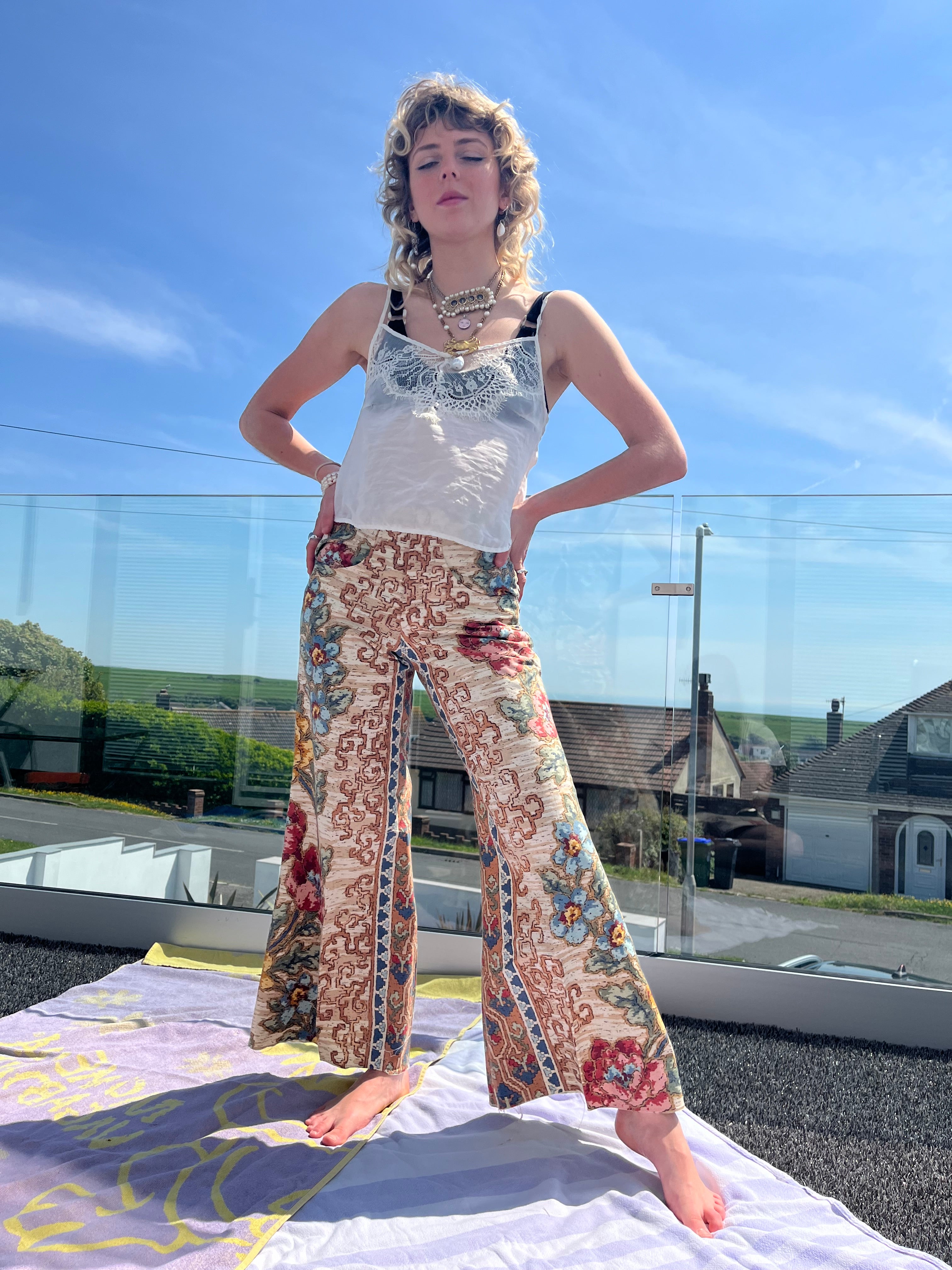 Person wearing a floral trouser standing outdoors with a clear blue sky.