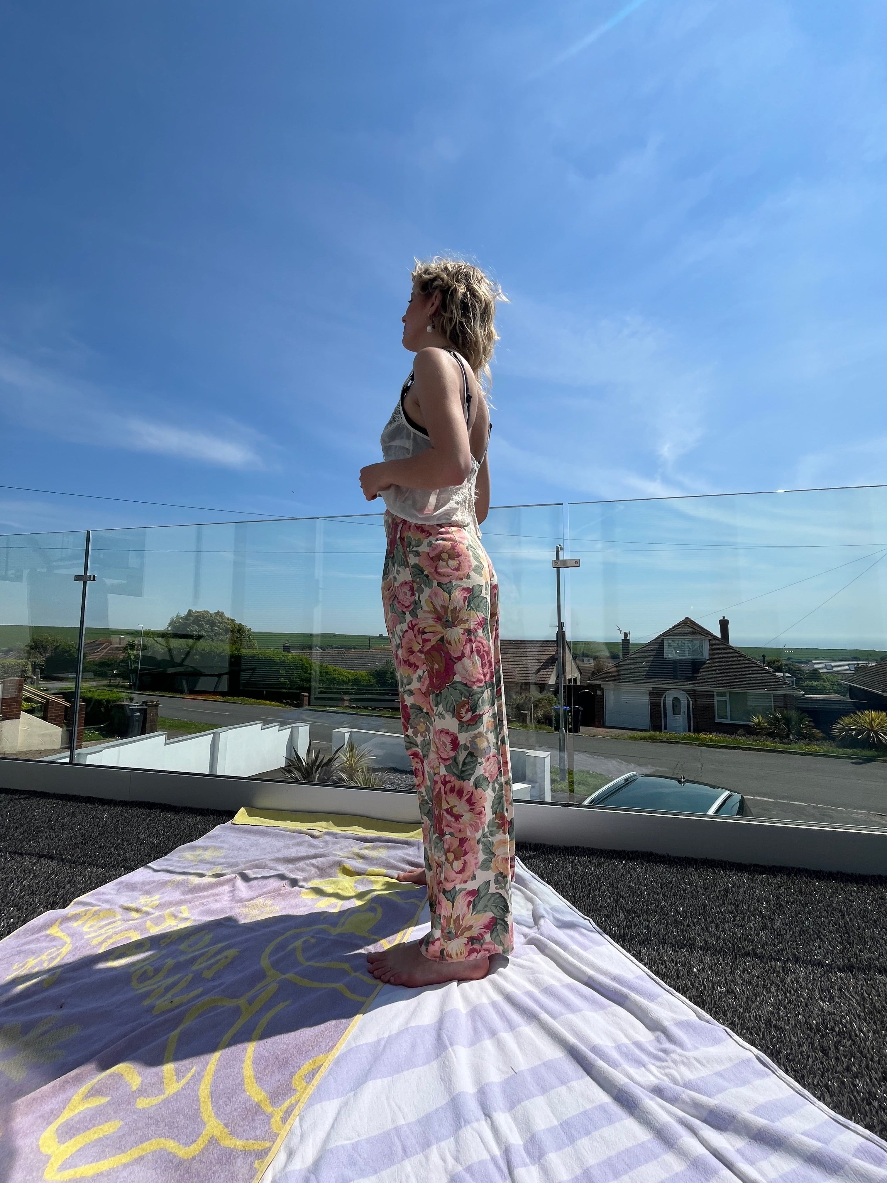 Person standing on a rooftop with a clear blue sky and buildings in the reflection.