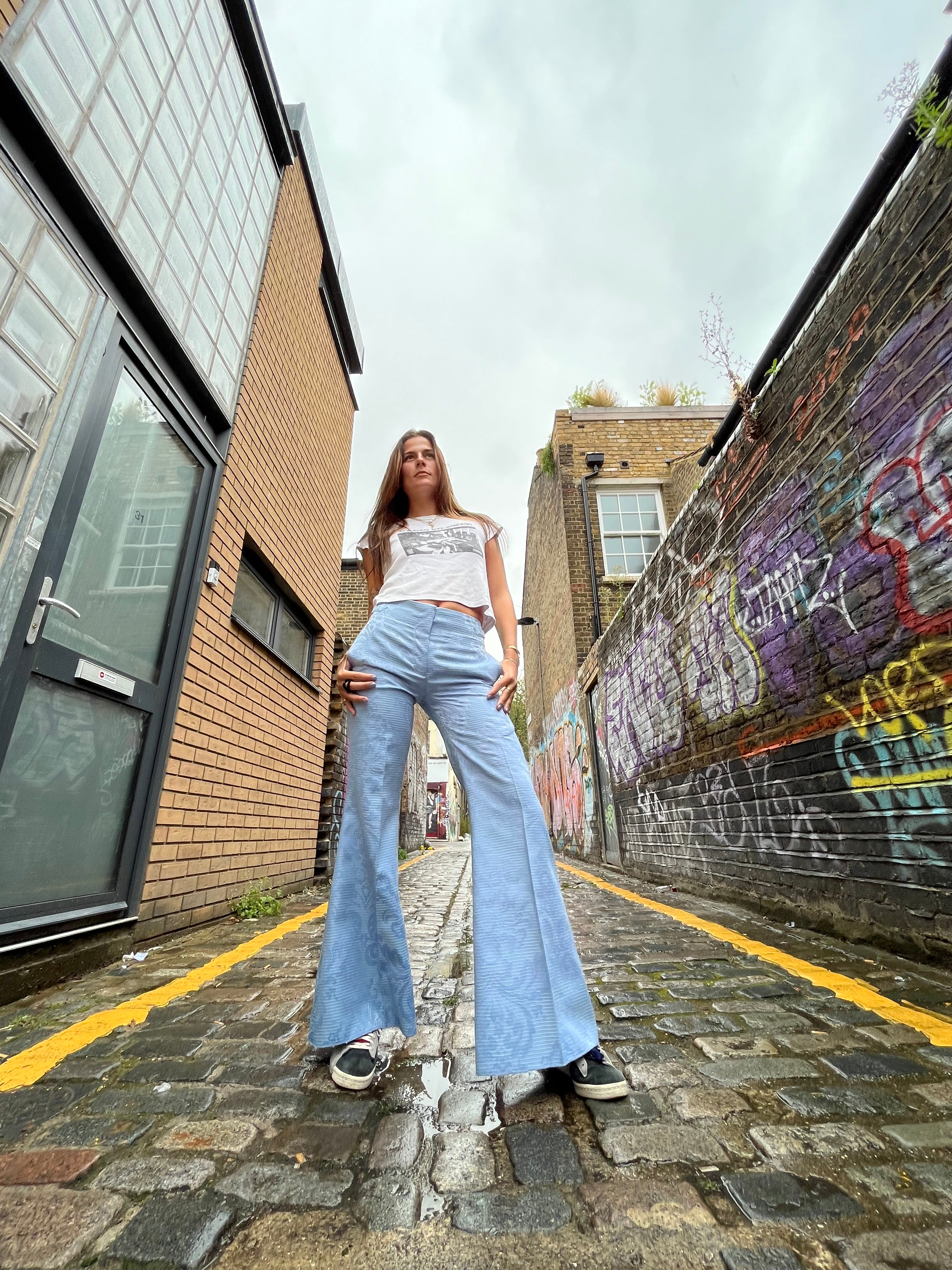 Person skateboarding in a narrow alley with graffiti on the walls