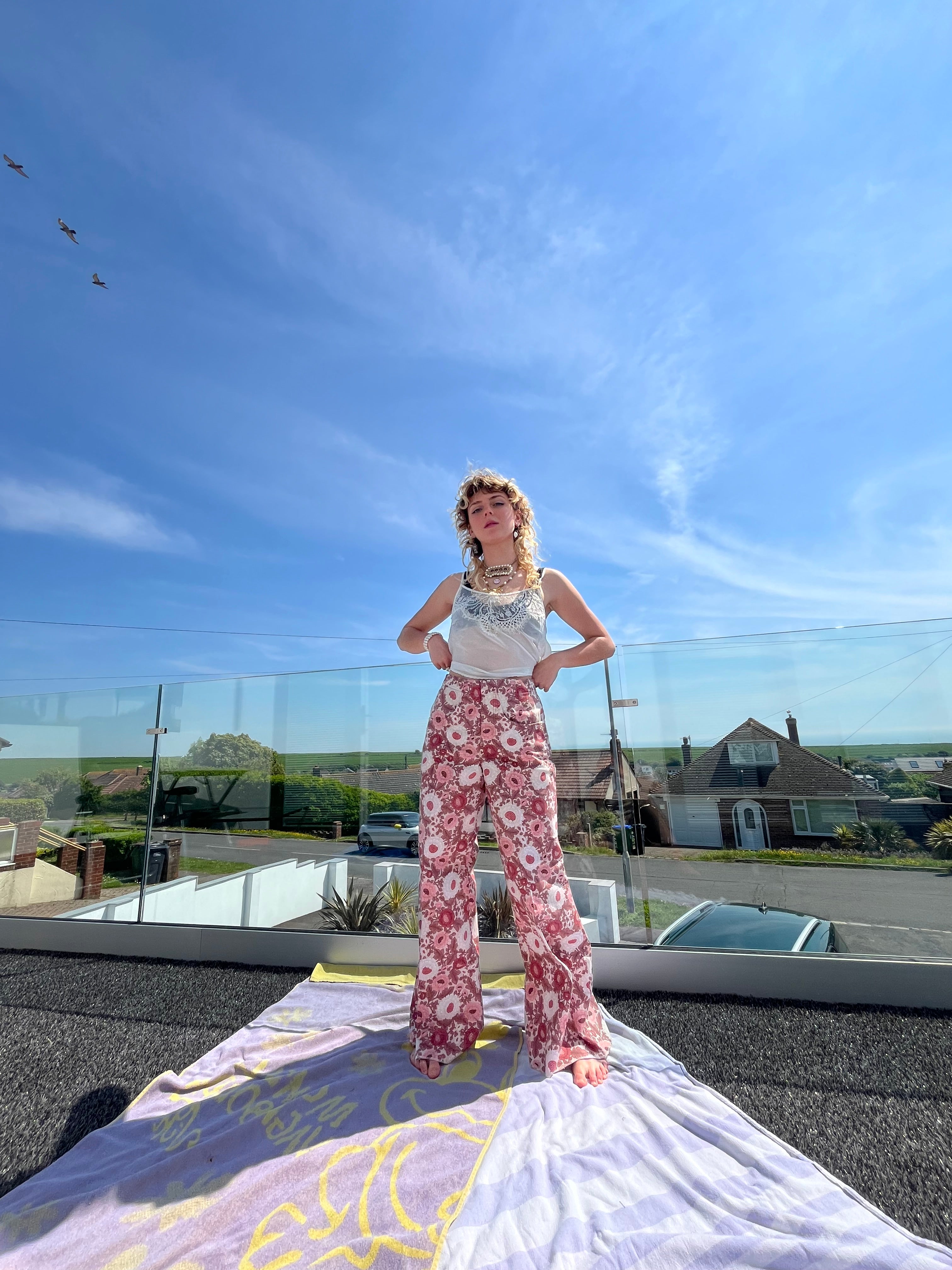 Person standing on a rooftop with a clear blue sky and sun rays.