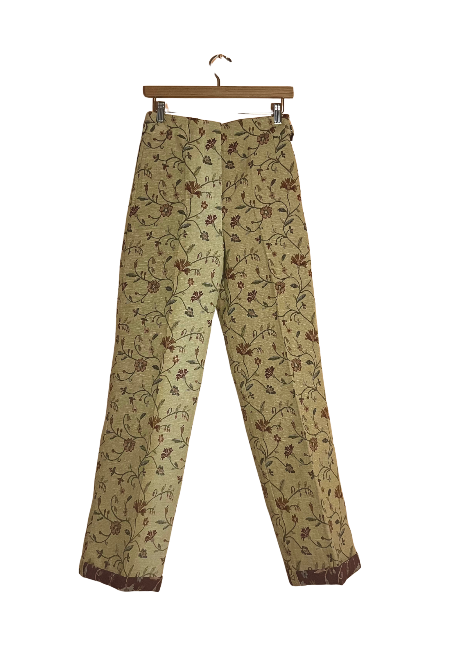 Floral-patterned pants on a hanger against a white background
