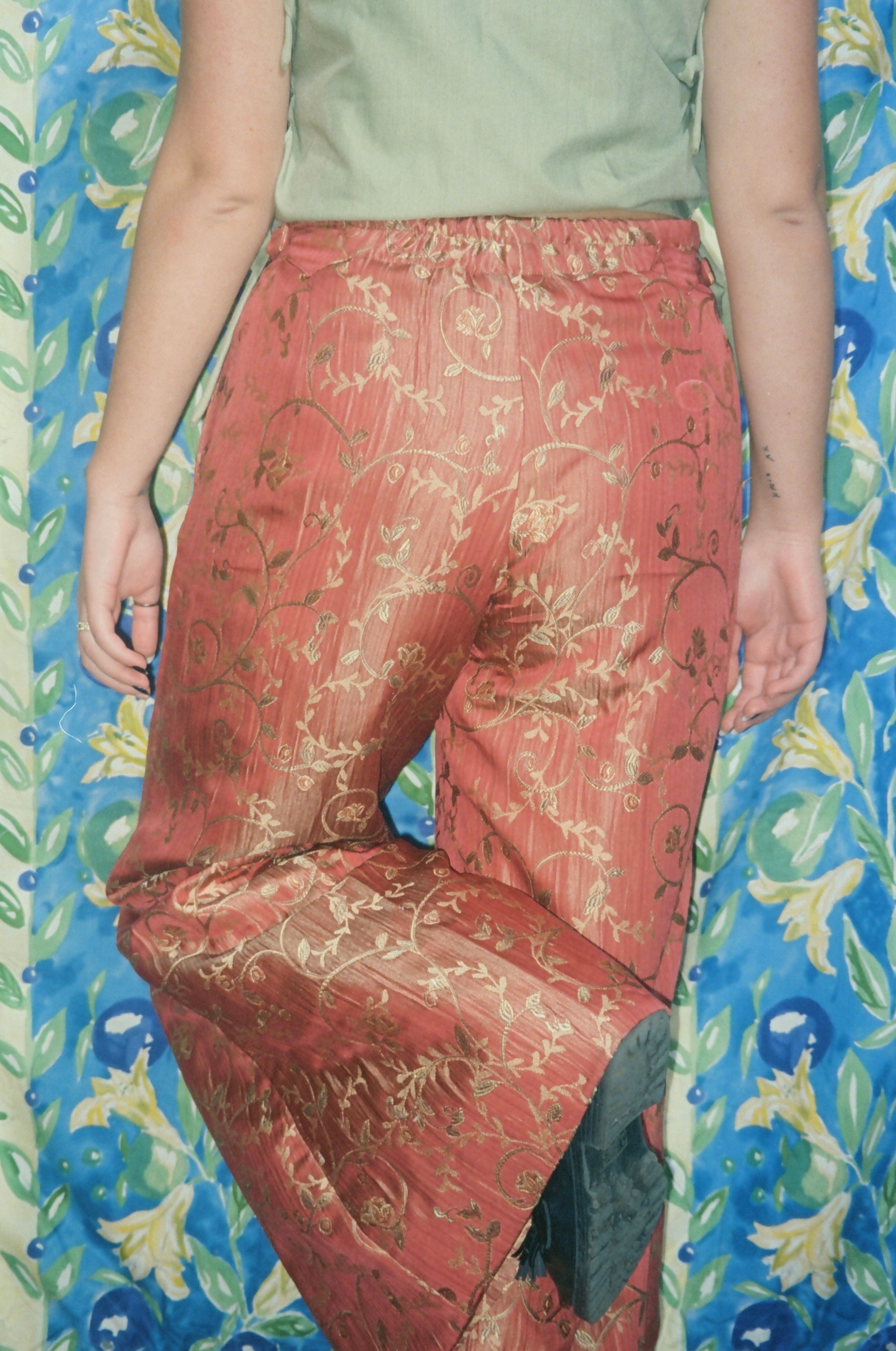 Person wearing red patterned pants on a colorful floral background