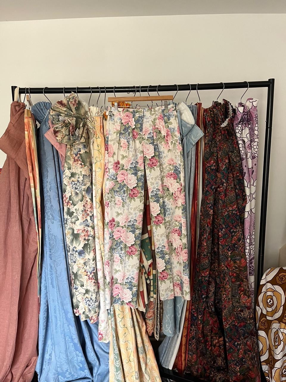 Collection of patterned clothing on a rack against a plain wall.
