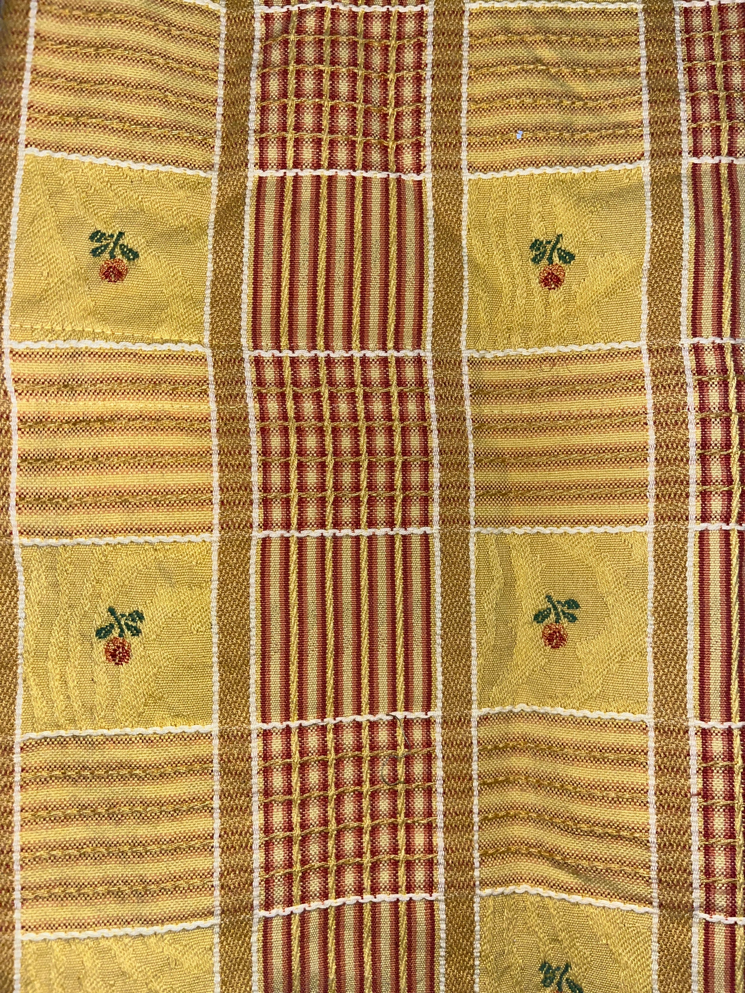 Textile with a checkered pattern featuring small embroidered designs on a green background.