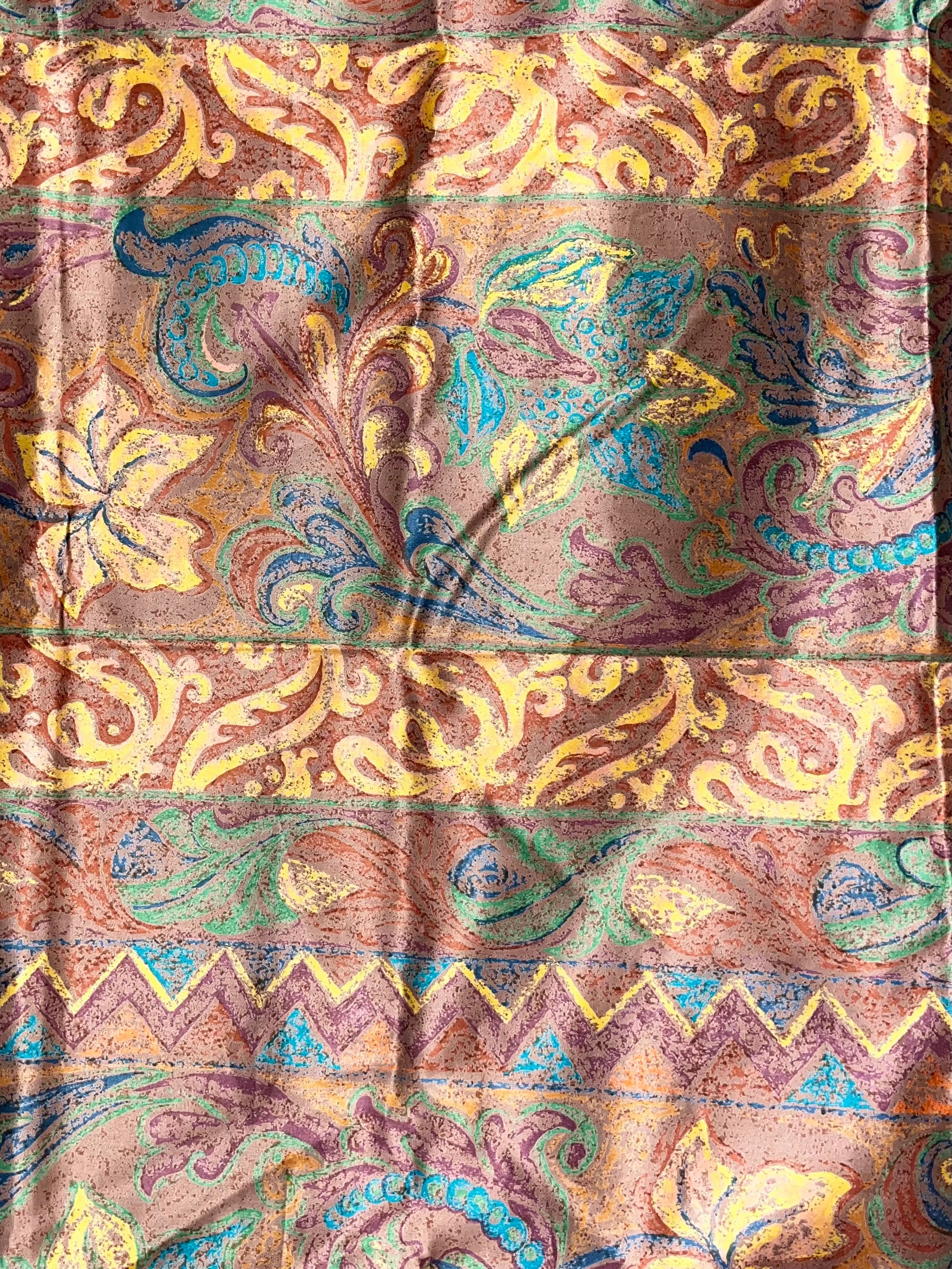 Patterned fabric with intricate designs in brown, yellow, and blue.